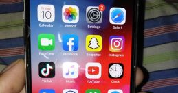 iPhone screen displaying various apps including TikTok, Facebook, Instagram, WhatsApp, and Netflix, held in a hand.