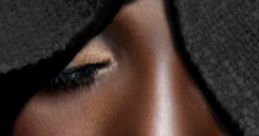 Close-up of a black woman's serene face, featuring smooth skin and subtle makeup, emphasizing natural beauty and elegance.