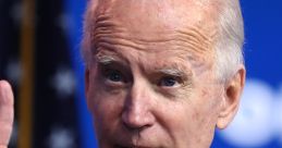 Joe Biden gestures while speaking, wearing a navy suit and red striped tie, with an American flag backdrop.