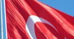 Turkish flag waving in the wind against a blue sky, symbolizing national pride and identity in Turkey.