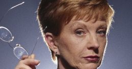 Confident performer Anne Robinson, host of The Weakest Link, holds glasses with a scrutinizing expression against a dark background.