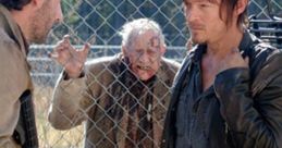 Rick and Daryl face a zombie threat behind a fence in a tense moment from The Walking Dead, highlighting survival challenges.