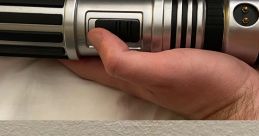 Silver and black lightsaber hilt held in hand, showcasing detailed design and activation switch, ideal for Star Wars fans.