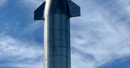 SpaceX Starship towering against a blue sky, showcasing its sleek design during a test launch phase at the facility.