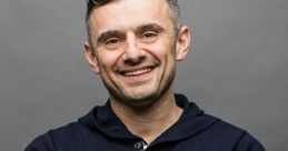 Gary Vee smiling, arms crossed, wearing a navy hoodie against a gray backdrop, exuding confidence and approachability.