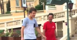 Young man riding a hoverboard on a street while an adult walks beside him, enjoying a sunny day outdoors.