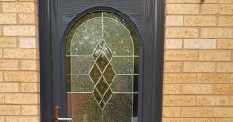 Elegant dark front door with decorative glass panel, enhancing curb appeal against a brick wall background.