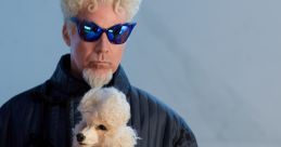 Man with unique hairstyle and blue sunglasses holding a fluffy poodle, styled in a fashion-forward outfit.