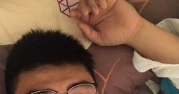 Young man in glasses relaxing on a bed with colorful pillows, showcasing a casual and laid-back vibe.