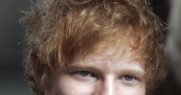 Smiling Ed Sheeran with tousled hair, wearing a black t-shirt, showcasing his approachable persona.