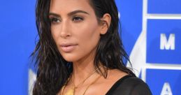 Kim Kardashian showcases a glamorous look with wet hair and layered gold jewelry at the VMAs, exuding confidence and style.