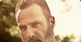 Rick Grimes with a rugged beard and intense gaze, surrounded by a natural backdrop, conveying strength and leadership.