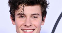 Shawn Mendes smiles broadly, showcasing his stylish outfit at a red carpet event, radiating charisma and charm.