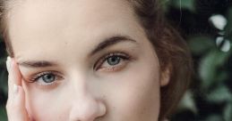 Portrait of a girl with soft features, wearing a cozy pink sweater, showcasing natural beauty against a green backdrop.