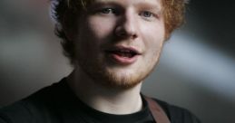 Ed Sheeran performing, wearing a black shirt with a Boba Fett design, playing an acoustic guitar and smiling.