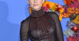 Melanie in a stunning black dress with red details, showcasing elegance at a floral-themed event backdrop.