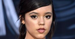 Jenna Ortega with a chic hairstyle and elegant black off-shoulder dress, showcasing her striking makeup and necklace.