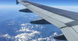 Airplane wing over stunning snow-capped mountains under a clear blue sky, showcasing aerial views from high altitude.