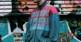 Young man in vintage tracksuit poses confidently against vibrant graffiti backdrop, embodying Gabber culture and style.