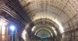 Underground train tunnel with tracks, illuminated walls, and electrical wiring, showcasing the structure of urban transit systems.