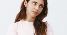 Woman with a displeased expression, arms crossed, conveying annoyance in a casual outfit against a simple background.