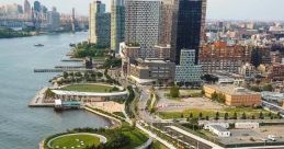 Aerial view of a waterfront area featuring park paths, greenery, and modern buildings along the river's edge.