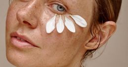 Natural beauty portrait featuring a woman with flower petals on her face, showcasing a fresh skincare aesthetic.