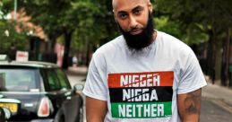 Man wearing a graphic t-shirt with a bold statement, posing confidently on a city street surrounded by greenery.