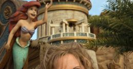 Jodi Benson smiles in front of Ariel's castle, celebrating her role as the voice of The Little Mermaid at a themed event.