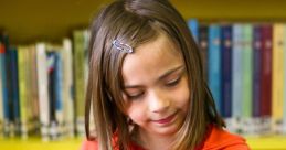 Young student in an orange shirt engrossed in a colorful book at a vibrant library filled with books.