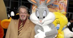 Joe Alaskey poses with Bugs Bunny and other Looney Tunes characters at a red carpet event, celebrating animated classics.