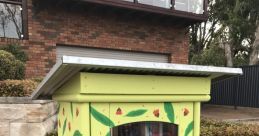 Colorful little free library on a residential street, filled with books and surrounded by lush greenery. Community reading space.