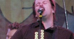 Jaret Reddick performing at Chuck E. Cheese, passionately singing into the microphone while playing guitar on stage.