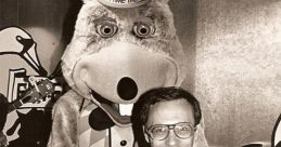 John Widelock poses with Chuck E. Cheese mascot, celebrating the family entertainment legacy from 1977 to 1983.