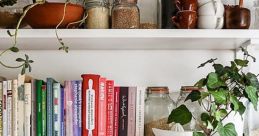 Organized kitchenware library with glass jars, terracotta bowls, cookbooks, and greenery for a stylish cooking space.