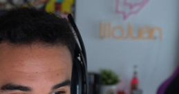 IlloJuan smiling while streaming, wearing a headset, with his logo visible in the background, creating engaging content.