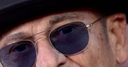 Joe Pesci poses confidently in a stylish black hat and sunglasses, showcasing his iconic look.