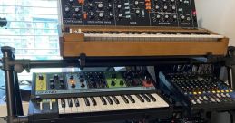 Close-up of a Synth One-Shop 3 library setup featuring various synthesizers and controllers on a multi-tiered stand.