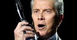 Michael Buffer, iconic wrestling ring announcer, holding a microphone and delivering an electrifying announcement in formal attire.