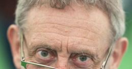 Michael Rosen with glasses, smiling gently, showcasing his thoughtful expression at an outdoor event.