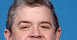 Patton Oswalt smiles in a casual setting, showcasing his distinctive hairstyle and warm personality.