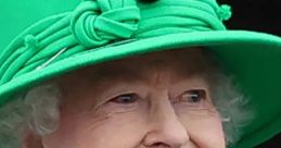 Queen Elizabeth II smiles gracefully, showcasing her iconic green outfit and elegant pearls at a public event.