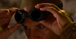 Richard B. Riddick adjusts his goggles, preparing for action in The Chronicles of Riddick, showcasing a fierce determination.