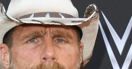 Shawn Michaels with a beard and cowboy hat, showcasing his signature style at a WWE event.