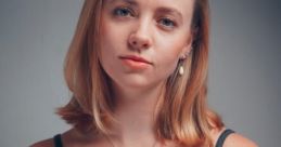 Portrait of a young woman with shoulder-length hair, wearing a gray tank top and pendant necklace, exuding confidence and elegance.