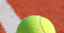 Bright green tennis ball resting on the red clay court, showcasing its fuzzy texture and distinctive yellow hue.