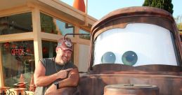 Larry the Cable Guy poses beside Tow Mater from Cars, showcasing the beloved character’s iconic smile and rustic charm.