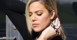 Khloe Kardashian poses elegantly in a black outfit, showcasing her stylish look and flawless makeup.