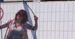 Woman in casual attire at a car wash, playfully wielding a hose, embodying a carefree summer vibe.