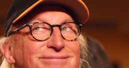 Otto Waalkes smiling with glasses and a cap, showcasing his iconic playful expression at an event.